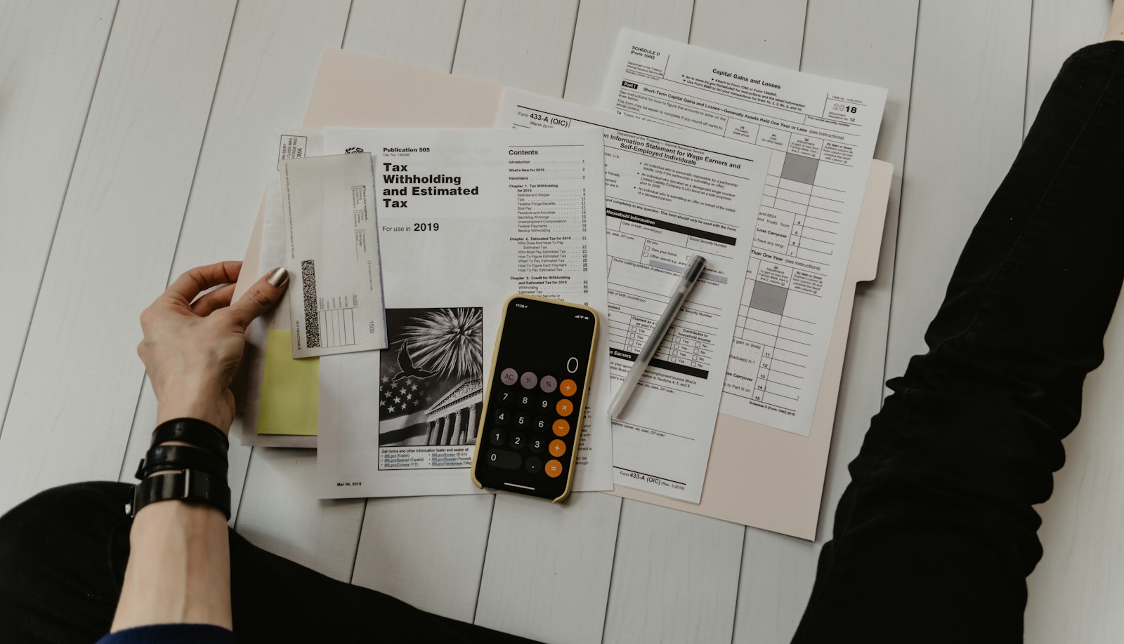 Person holding paper near pen and calculator